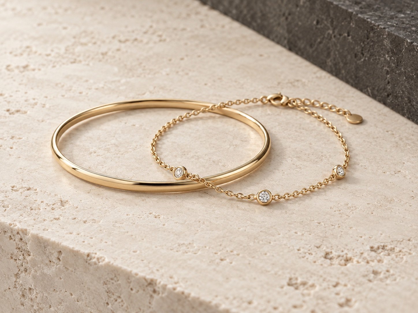 Duas pulseiras douradas da Meiry Martins sobre pedra clara